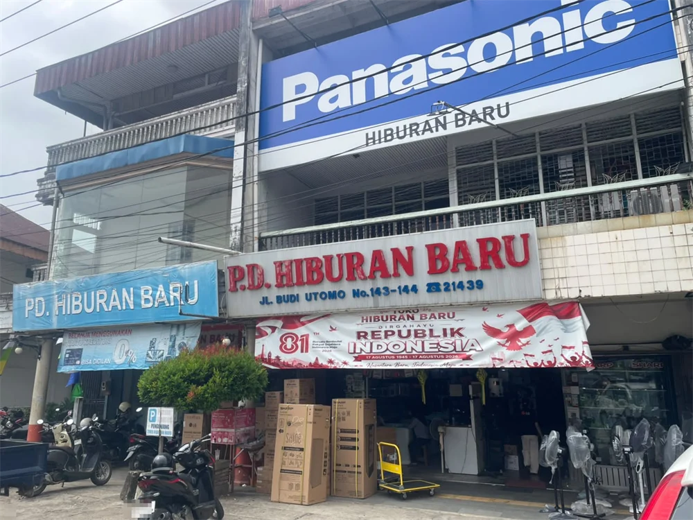 Tampak depan toko elektronik Hiburan Baru di Jalan Budi Utomo, Singkawang, dengan papan nama, dus barang, dan kipas angin dipajang di depan toko